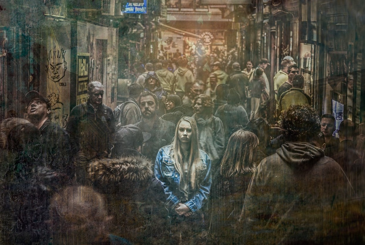 Femme immobile au milieu de la foule, illustrant le sentiment d’angoisse, de solitude et de surcharge mentale accompagnés par un psychologue à Aubagne.